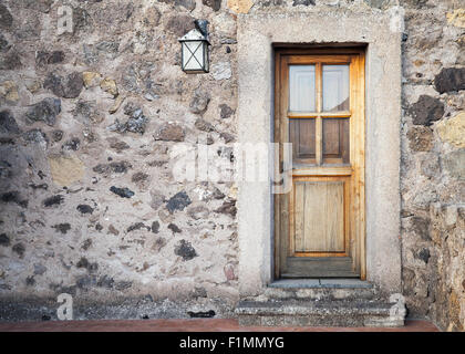 Alte Holztür mit Straßenlaterne auf Steinwand, Foto Hintergrundtextur Stockfoto