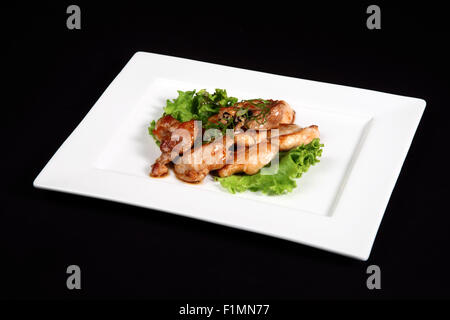 Gegrilltes Hähnchen mit Gemüse in weißer Teller auf einem schwarzen Hintergrund Stockfoto