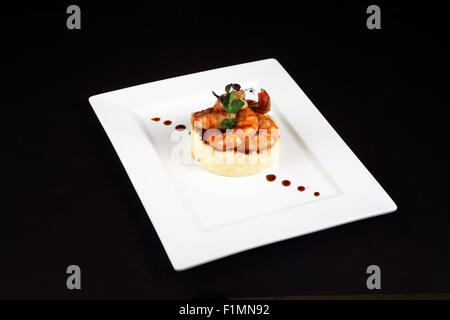 gut Gericht mit Garnelen in weißer Teller auf schwarzem Hintergrund Stockfoto