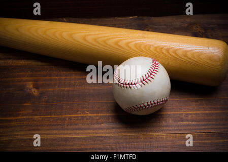 Baseball-Ausrüstung: hölzerne Schläger und Ball auf einem hölzernen Brett oder Bank Hintergrund Stockfoto