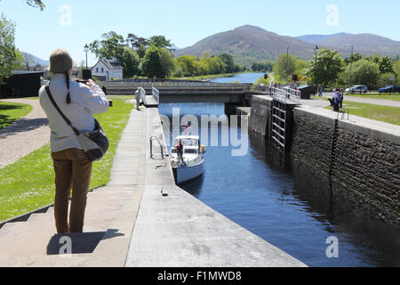 Frau Tourist nimmt ein Foto von einem Boot in Neptuns Treppe, auf der Caledonian Canal, Schottland. Stockfoto