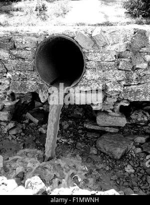 Monochrome Ansicht das schmutzige Wasser fließt aus einem braunen rostigen Rohren Stockfoto