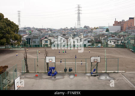 Japanische Junior High School Kinder spielen im Dreck Schule Feld mit Basketball-Courts im Vordergrund Stockfoto