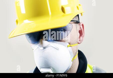Auftragnehmer Gesicht Nahaufnahme. Auftragnehmer im gelben Helm, Schutzbrille und Sicherheit Atemmaske. Stockfoto