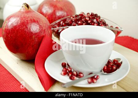 Granatapfel Tee, Obst und Granatapfelkernen auf Holzplatte. Gesunden Granatapfel Tee in die weiße Tasse. Essen und Getränke Foto Col Stockfoto