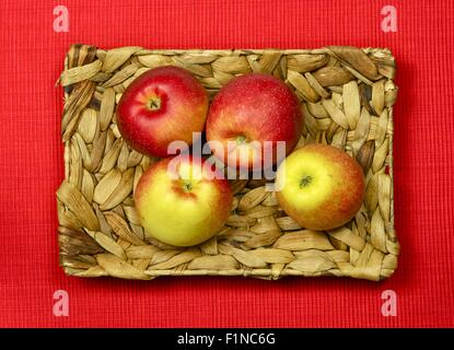 Frischer Garten Äpfel im Korb. Roter Stoff im Hintergrund. Ansicht von oben Foto. Essen-Fotosammlung. Stockfoto