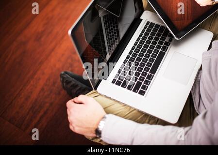 Männer mit Laptop und Tablet-Computer arbeiten auf das Parkett. Junger Geschäftsmann mit Computergeräten. Tägliche Technologie Pho Stockfoto