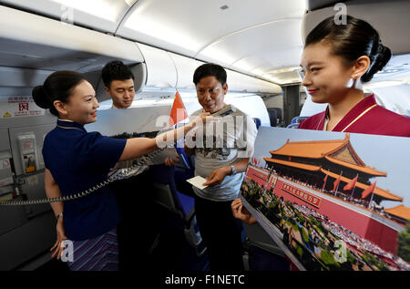 (150905)--Peking, 5. September 2015 (Xinhua)--A Flight Attendant (R) zeigt Fotos von Peking Day Parade auf dem Flug CZ6366 von Peking, Hauptstadt von China, nach Haikou, der Hauptstadt der Provinz Süd-China Hainan, 5. September 2015. China Southern Airlines begann eine Veranstaltung namens "In Gedenken an Peking Day Parade" auf einem Flug von Beijing-Haikou Samstag, Parade Fotos für Passagiere. China am Donnerstag statt Gedenken Aktivitäten, einschließlich einer großen Militärparade anlässlich der 70. Jahrestag des Sieges von dem chinesischen Volk Krieg des Widerstands gegen die japanische Aggression und die Stockfoto