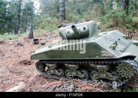 eine horizontale Ansicht eines Radiocontrol-Panzers und ein Helm im Hintergrund in einem Wald Stockfoto