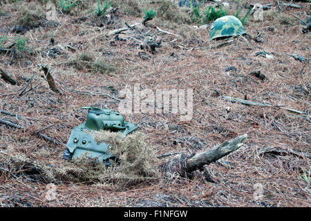 eine horizontale Ansicht eine Radiocontrol-Panzer und einen Helm in einem Wald Stockfoto