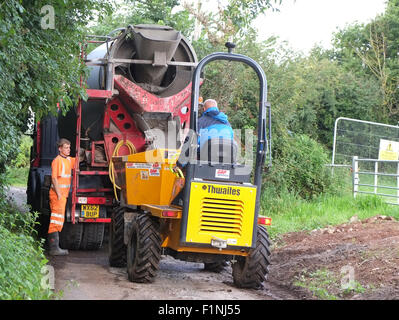 Entladen ein konkreten LKW in einen schmalen Feldweg in einen kleinen Bauherren-Kipper für die Platzierung auf einem Bauernhof Stockfoto