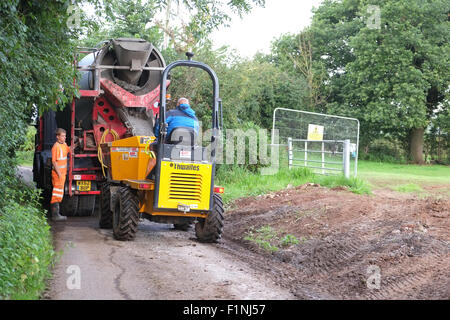 Entladen ein konkreten LKW in einen schmalen Feldweg in einen kleinen Bauherren-Kipper für die Platzierung auf einem Bauernhof Stockfoto