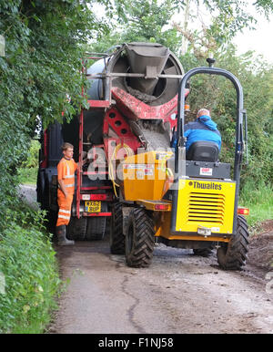 Entladen ein konkreten LKW in einen schmalen Feldweg in einen kleinen Bauherren-Kipper für die Platzierung auf einem Bauernhof Stockfoto