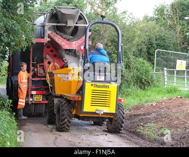 Entladen ein konkreten LKW in einen schmalen Feldweg in einen kleinen Bauherren-Kipper für die Platzierung auf einem Bauernhof Stockfoto