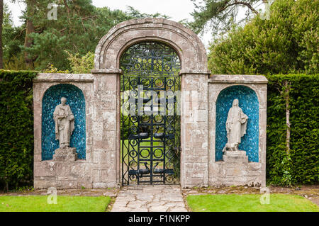 Zwei Statuen auf beiden Seiten ein Stahltor und steinernen Torbogen in einem formalen Garten Stockfoto