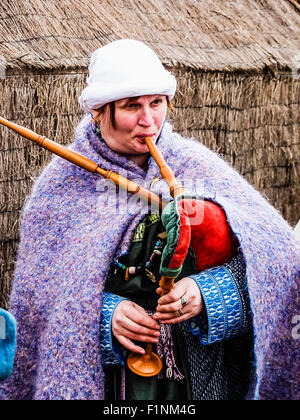 Eine Frau gekleidet in mittelalterliche Kleidung spielt eine traditionelle Reihe von Dudelsack. Stockfoto