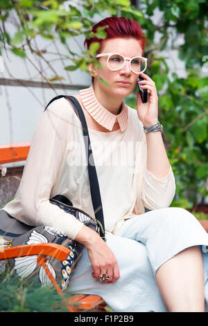 rothaarige Frau sitzen auf einer Bank und am Telefon sprechen Stockfoto