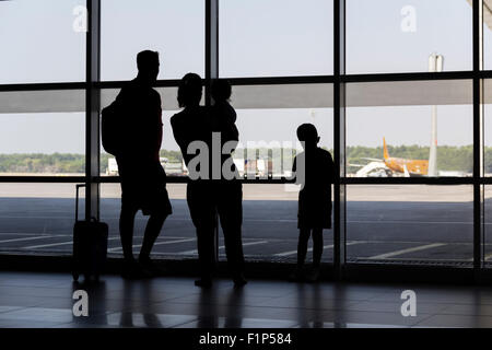 Silhouette-Familie am Flughafen vor Fenster Flugzeuge starten und landen beobachten Stockfoto