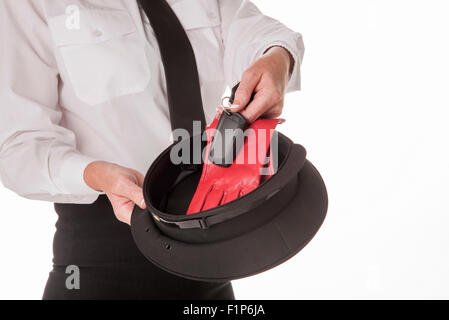 Ein uniformierter Chauffeuse stehende hält einen schwarzen Hut und treibende Handschuhe halten. Einem professionellen weiblichen chauffeur Stockfoto