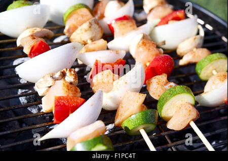 Schaschlik Grill - Hähnchen Fleischscheiben mit Gemüse. Saftige Scheiben Hühnerfleisch mit Sauce zubereiten in Brand. Stockfoto