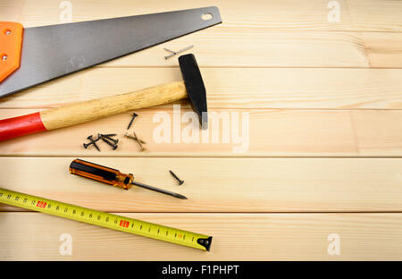 Schraube, Maßband, Säge und Hammer auf Holz Stockfoto
