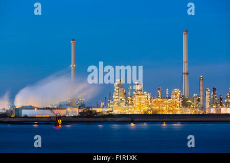 Blick über die Schelde in Antwerpen, Belgien, eine große Erdölraffinerie mit blauen Nachthimmel, Beleuchtung und Dampf. Stockfoto