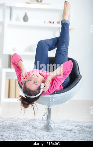 Frau hören über Kopfhörer während auf einem Stuhl Stockfoto