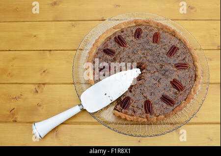 Tortenheber in einer in Scheiben geschnittenen hausgemachte Pekannuss-Torte auf einem Holztisch Stockfoto