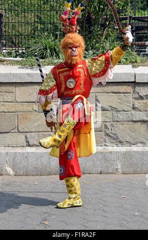 Foto eines asiatischen Straßenmusikers in einem bunten Simian gekleidet Kostümentanz für Spenden im Union Square Park in New York City Stockfoto