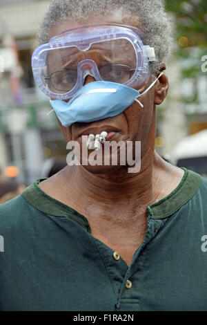 Mann, drei Zigaretten gleichzeitig Rauchen, beim Tragen von Schutzbrillen & eine Maske in Union Square Park in New York City Stockfoto