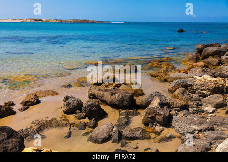 Wasser mit großen Steinen auf dem Sand und Blick auf die ruhige See Gewässer Stockfoto