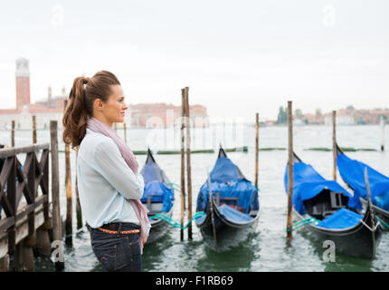 Eine Frau steht, Träumen der Vergangenheit hören auf den Klang des Wassers gegen die festgemachten Gondeln Läppen. Stockfoto