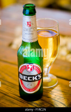 Becks Bierflasche und Glas auf einem Holztisch. Stockfoto