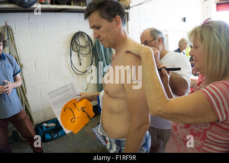 Isle Of Wight, UK, Samstag, 15. August 2015. Mitglieder des London Polytechnic Teams auf der jährlichen Sandown, Shanklin schwimmen. Sandown, Shanklin Meer schwimmen ist Gezeiten betreutes Schwimmen 2 Meile auch bekannt als das Pier, Pier-schwimmen. Registrierung und Nummerierung. Stockfoto