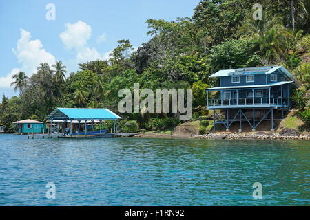 Off Grid Waterfront home auf üppige tropische Küste mit Boot im Dock auf einer Insel der Inselgruppe Bocas del Toro, Panama Stockfoto