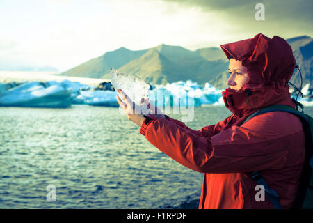 Frau hält ein Stück Eis vom Gletscher am Jökulsárlón Lagune in Island Stockfoto