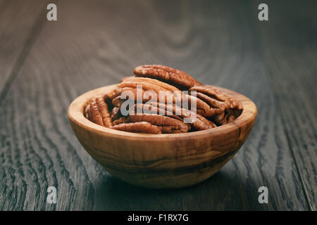 Pekannüsse in Oliven Holz Schüssel auf Eichentisch Stockfoto