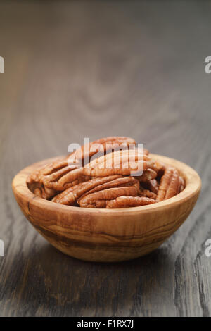 Pekannüsse in Oliven Holz Schüssel auf Eichentisch Stockfoto