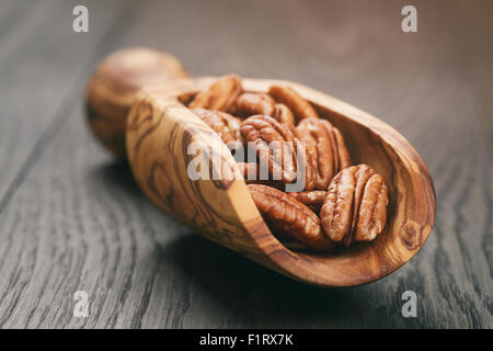 Pekannüsse in Oliven Holz Schaufel auf Eichentisch Stockfoto