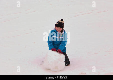 Kleines Mädchen im Winter-Aktivität mit einem großen Schnee-Ball. Konzept der Winter-Aktivität von Kindern genossen. Stockfoto