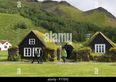 Touristen, die zwischen den traditionellen Rasenhäusern oder torfbæir auf Isländisch spazieren gehen, im Skógarsafn - Skogar Regional Museum in Island Stockfoto