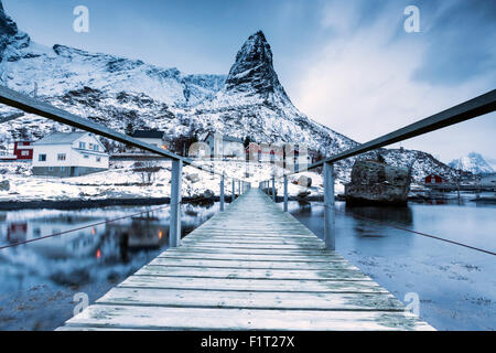 Eine Brücke über dem kalten Meer verbindet ein typisches Fischerdorf. Reine, Lofoten-Inseln, Nord-Norwegen, Skandinavien, Arktis Stockfoto