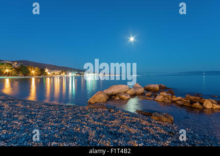 Kleine Stadt am Meer durch das Mondlicht mit klaren blauen Himmel nachts beleuchtet. Stockfoto