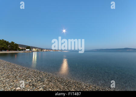 Kleiner Kiesstrand am Adriatischen Meer in der Nacht mit Crikvenica Stadt im Hintergrund Stockfoto