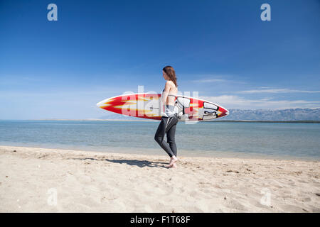Frau mit Surfbrett am Strand Stockfoto