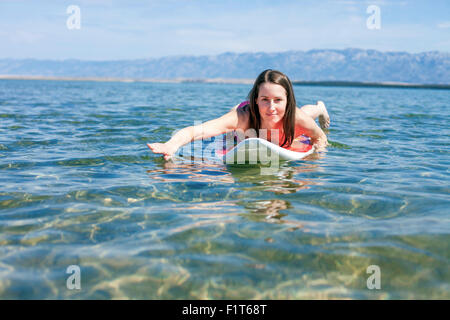 Frau liegend auf Surfbrett Stockfoto