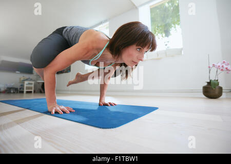 Reife Fitness Frau auf Händen mit Füßen hochgehoben Kran Yoga-Pose - Bakasana zu tun. Frau tut Hände Stand auf Übung Stockfoto