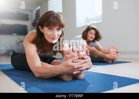 Frauen, die zusammen im Fitness-Studio, Yoga üben Paschimottanasana darstellen. Fitness Frauen sitzen nach vorne beugen Haltung während des Trainings ses Stockfoto