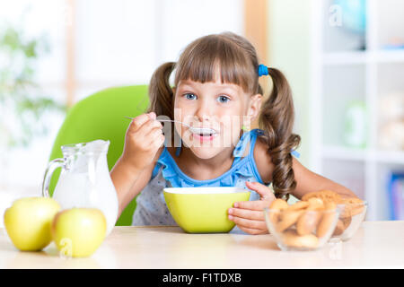 niedliche kleine Mädchen essen Müsli mit Milch im Kindergarten Stockfoto