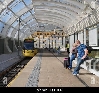 Menschen warten auf die Straßenbahn an der Haltestelle Metrolink Victoria Bahnhof, Manchester, UK. Stockfoto